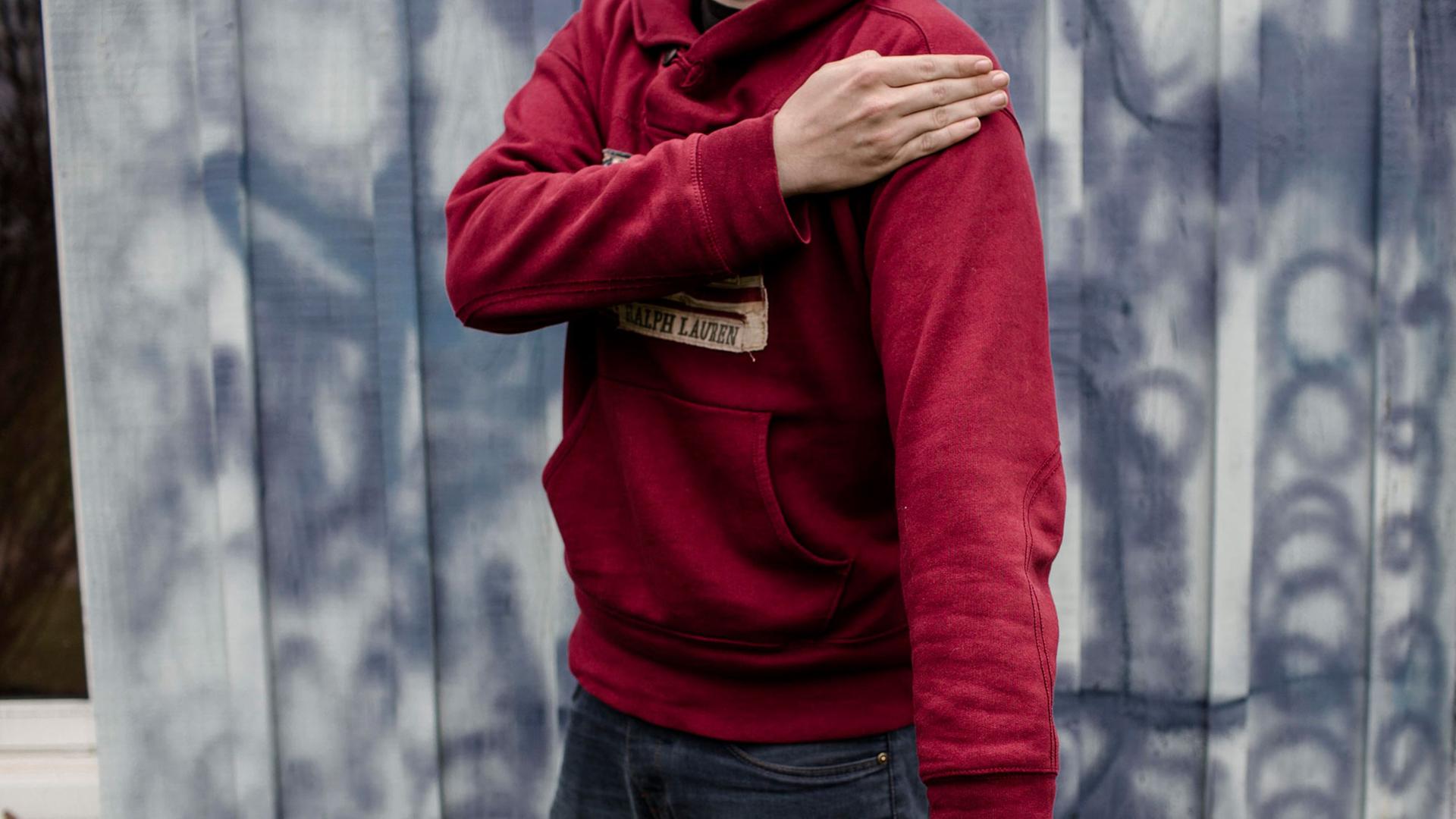 Ein junger Mann demonstriert den Quenelle-Gruß: rechter Arm mit ausgestreckter Hand nach unten gestreckt, linke Hand gegen den rechten Oberarm gelegt. Ein junger Mann demonstriert den Quenelle-Gruß: rechter Arm mit ausgestreckter Hand nach unten gestreckt, linke Hand gegen den rechten Oberarm gelegt.