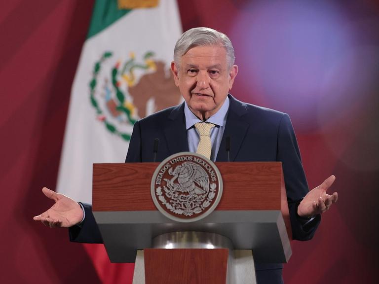Der mexikanische Präsident Andres Manuel Lopez Obrador steht an einem Pult und spricht, im Hintergrund die mexikanische Flagge.