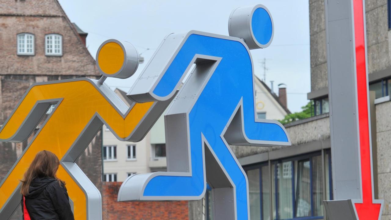 Eine Frau geht in Ulm an überdimensioniertem Piktogrammen vorbei. Diese Piktogramnme wurden von Ottl Aicher an der Ulmer Hochschule für Gestaltung (HfG) entworfen. Eine Frau geht in Ulm an überdimensioniertem Piktogrammen vorbei. Diese Piktogramnme wurden von Ottl Aicher an der Ulmer Hochschule für Gestaltung (HfG) entworfen.