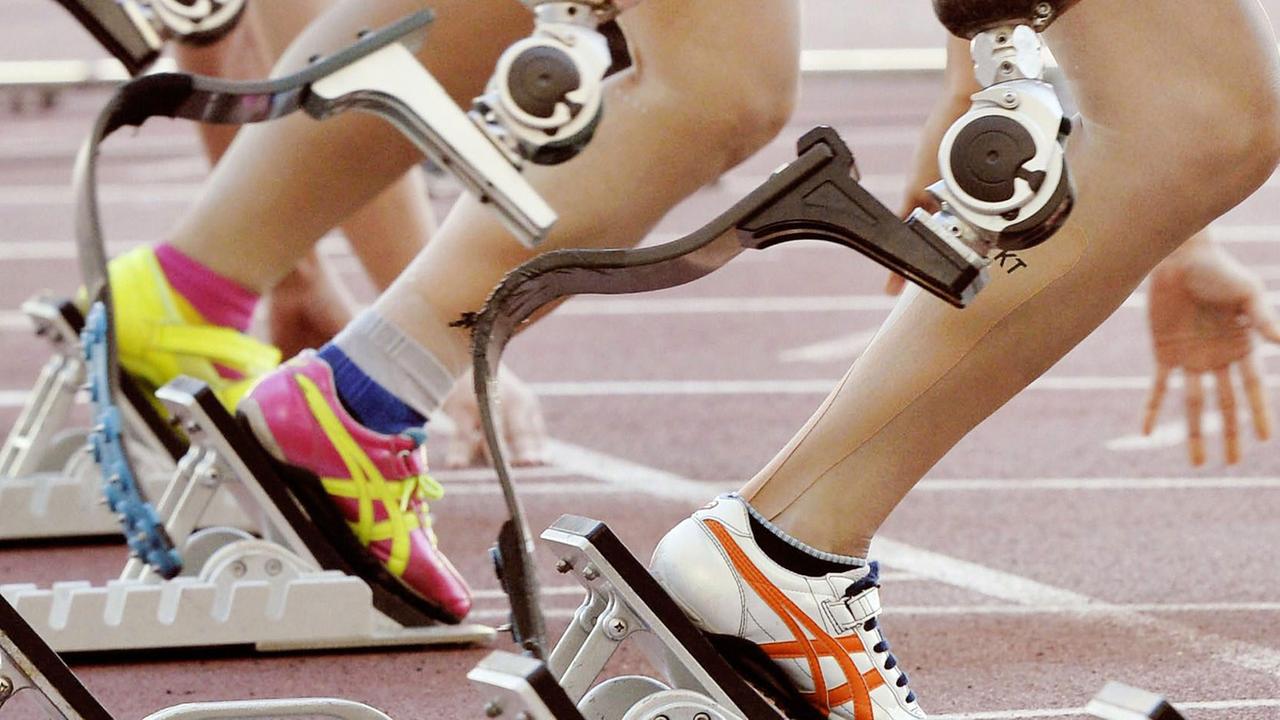 Athletinnen mit Beinprothesen sind bereit für einen Sprintwettkampf. Sie stehen im Start. Athletinnen mit Beinprothesen sind bereit für einen Sprintwettkampf. Sie stehen im Start.