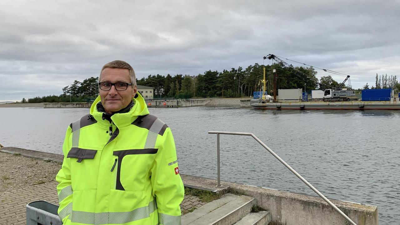 Lubminer Bürgermeister Axel Vogt steht in einer gelben Warschutzjacke am Ufer. Lubminer Bürgermeister Axel Vogt steht in einer gelben Warschutzjacke am Ufer.