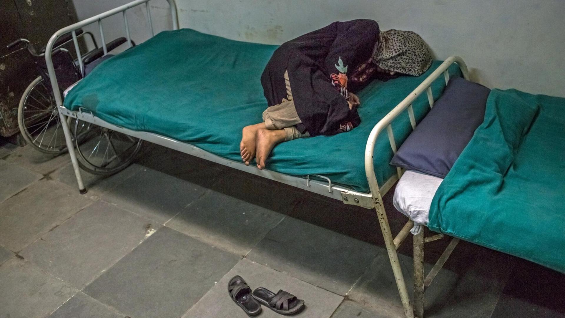 Eine Schizophrenie-Patientin liegt auf einem Bett in einer psychiatrischen Klinik in Indien Eine Schizophrenie-Patientin liegt auf einem Bett in einer psychiatrischen Klinik in Indien