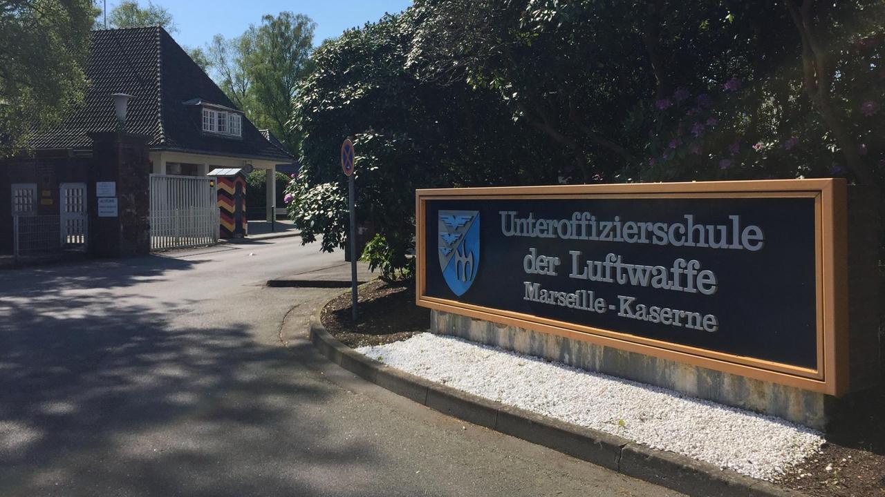 Asphaltierte Einfahrt zu einer Kaserne der Bundeswehr. Auf der rechten Seite steht eine große Tafel. Darauf prangt der Name des Standorts: "Marseille-Kaserne". Asphaltierte Einfahrt zu einer Kaserne der Bundeswehr. Auf der rechten Seite steht eine große Tafel. Darauf prangt der Name des Standorts: "Marseille-Kaserne".