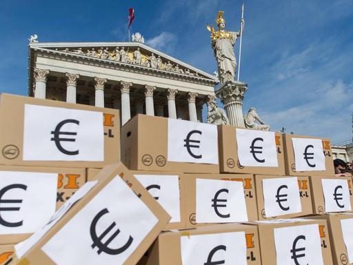 Demonstranten haben in Wien Kartons zu einer Mauer aufgestapelt, auf denen das Eurozeichen prangt.