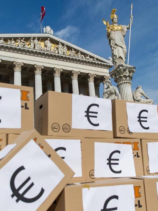 Demonstranten haben in Wien Kartons zu einer Mauer aufgestapelt, auf denen das Eurozeichen prangt.