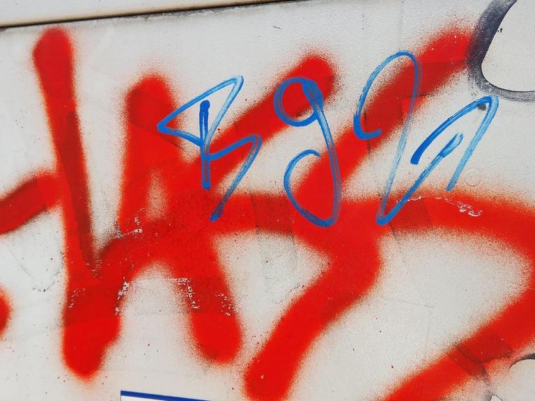 Das Wort "Hass" steht gesprüht in roter Farbe auf einem Stromkasten