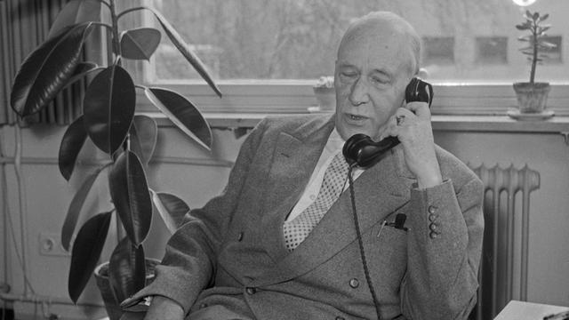 Der Schriftsteller, Erzähler und Drehbuchautor Dr. Walther von Hollander sitzt telefonierend in seinem Büro in Hamburg, Aufnahme von 1956