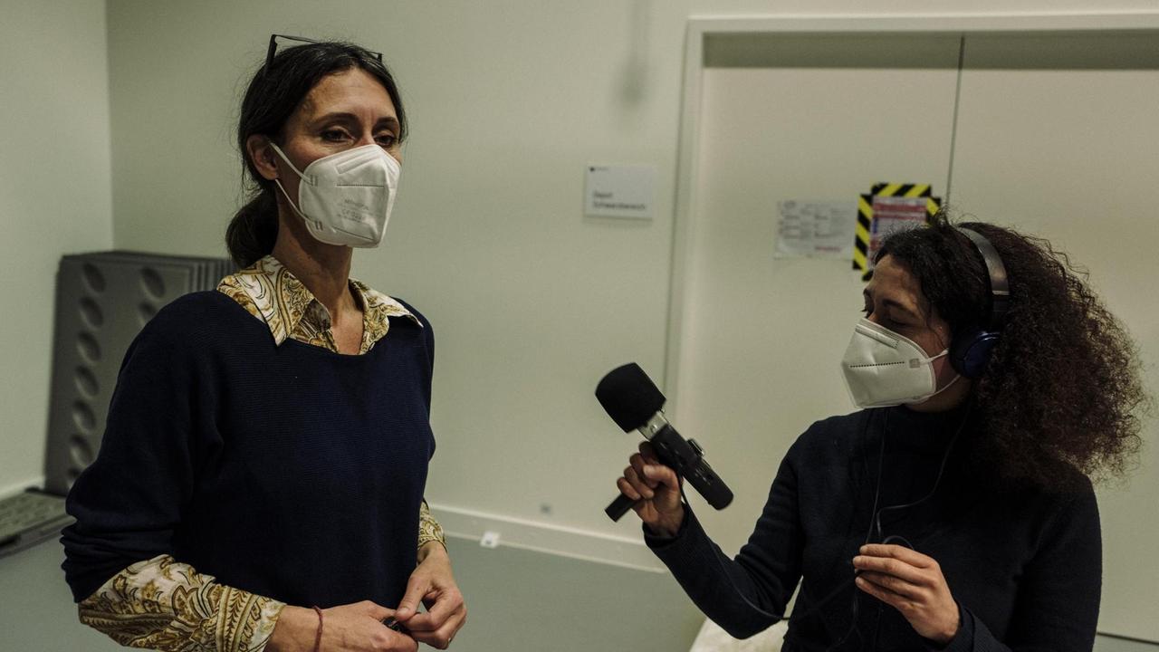 Links steht die Leiterin der Werkstätten Melanie Münchau die von der Autorin Aureliana Sorrento interviewt wird. Beide tragen FFP2-Masken.