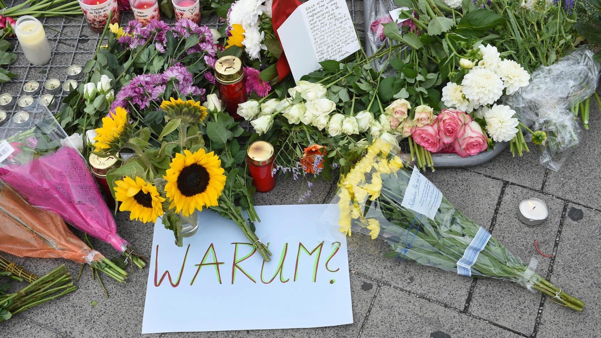 Ein Schild mit der Aufschrift "Warum" liegt nahe des Olympia-Einkaufszentrums in München, wo ein Amokläufer neun Menschen erschossen hat. Ein Schild mit der Aufschrift "Warum" liegt nahe des Olympia-Einkaufszentrums in München, wo ein Amokläufer neun Menschen erschossen hat.