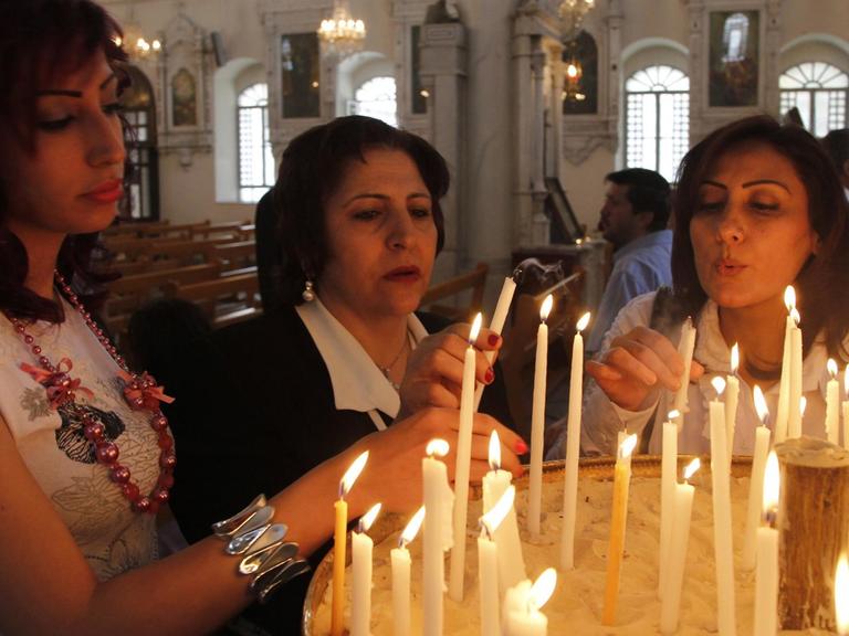 Orthodoxe Christen entzünden in einer Kirche in Damaskus, Syrien, Kerzen.