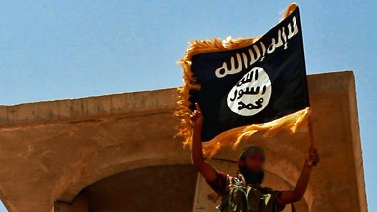 Ein Anhänger des IS mit der Flagge der Miliz Ein Anhänger des IS mit der Flagge der Miliz