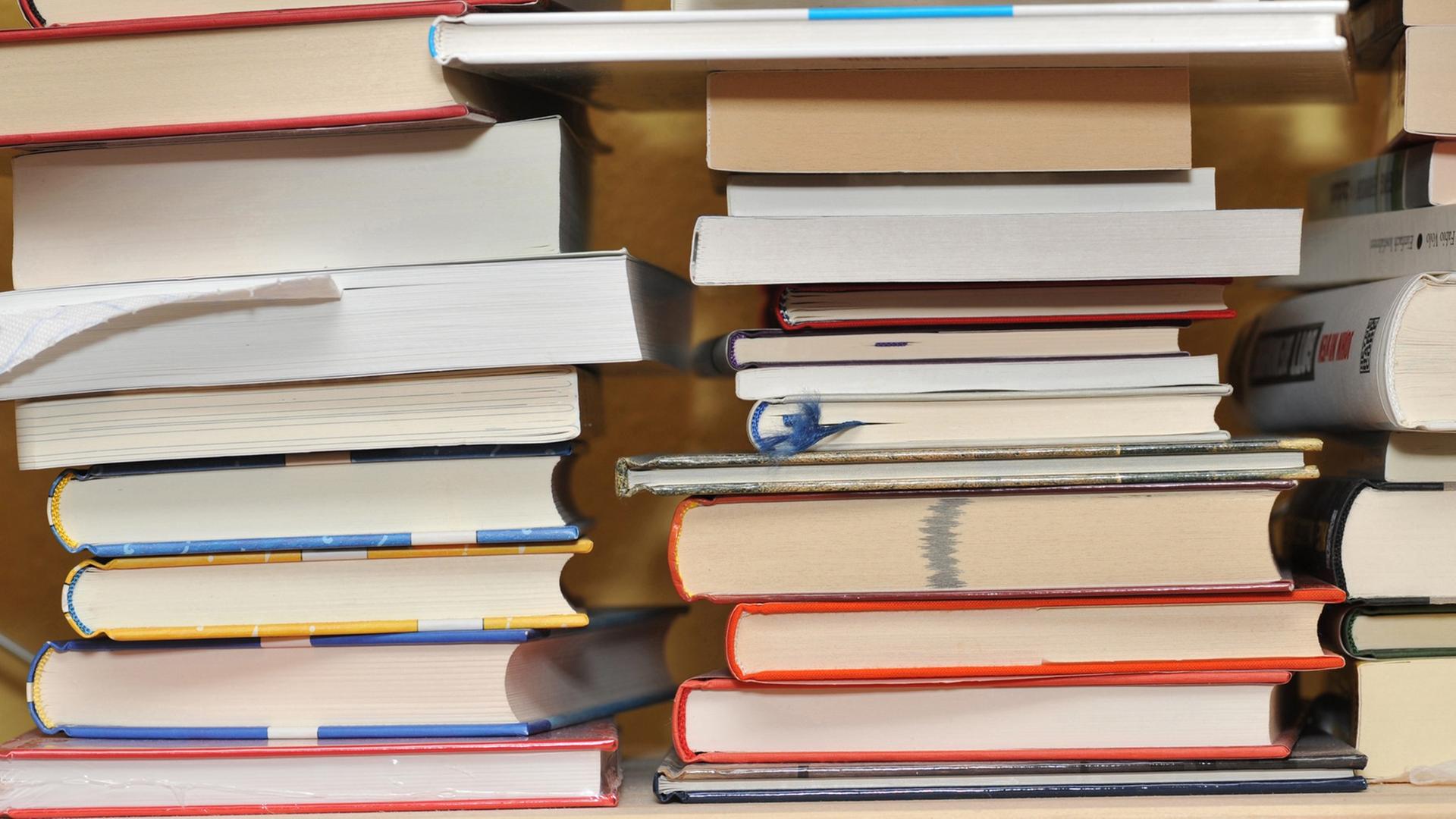 Mehrere Bücher liegen auf drei Stapeln nebeneinander. Mehrere Bücher liegen auf drei Stapeln nebeneinander.