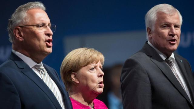 Angela Merkel, Joachim Herrmann und Horst Seehofer singen die Nationalhymne.