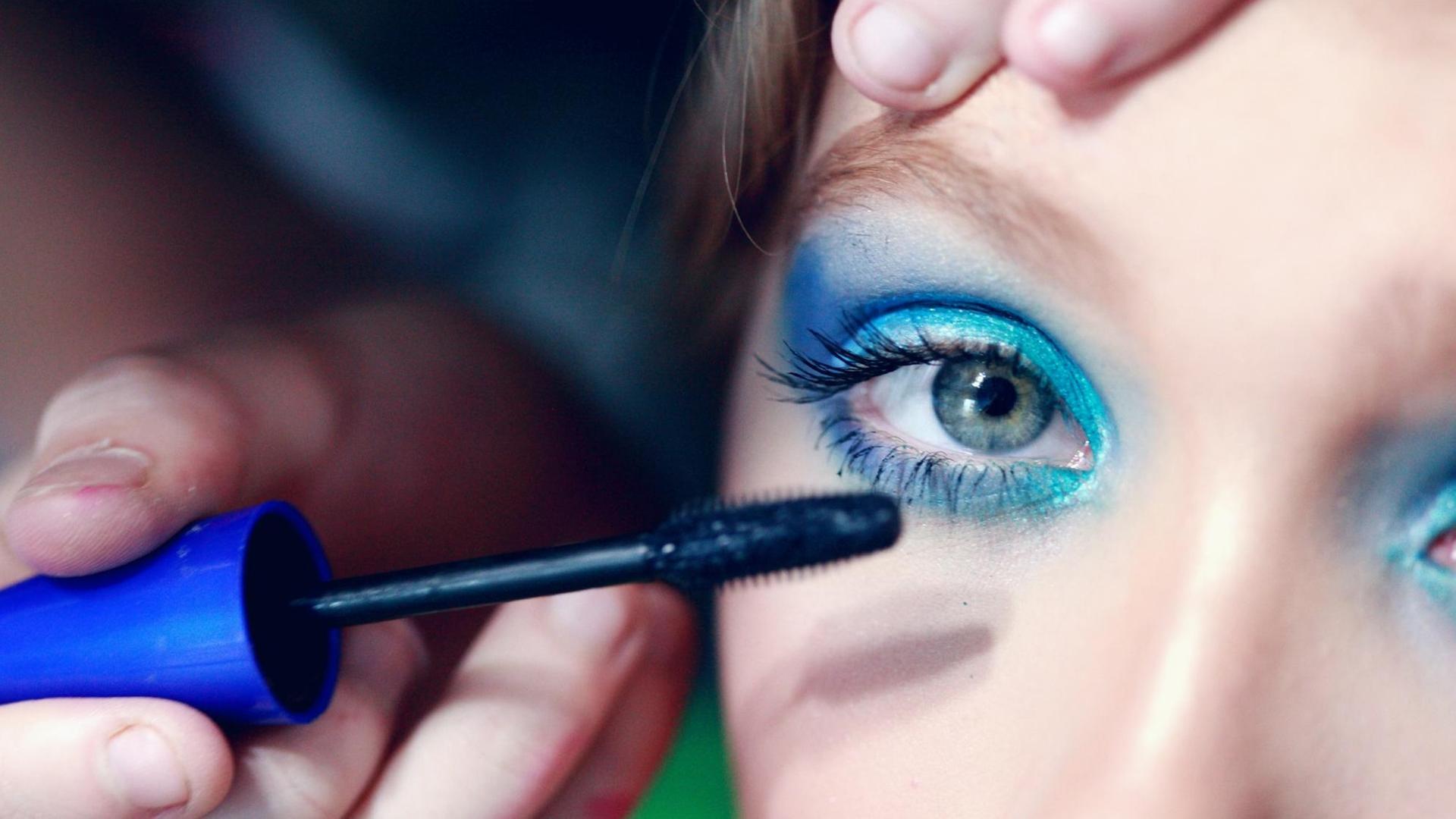 Ein Kind schminkt sich mit blauer Wimperntusche. Ein Kind schminkt sich mit blauer Wimperntusche.