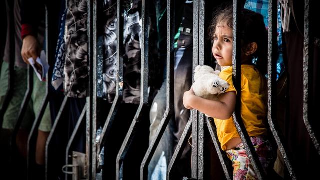 Die kleine Farah wartet mit ihren Eltern aus dem Irak auf der griechischen Insel Kos vor einer Polizeistation, um herauszufinden, ob sie als Flüchtlinge registriert wurden.