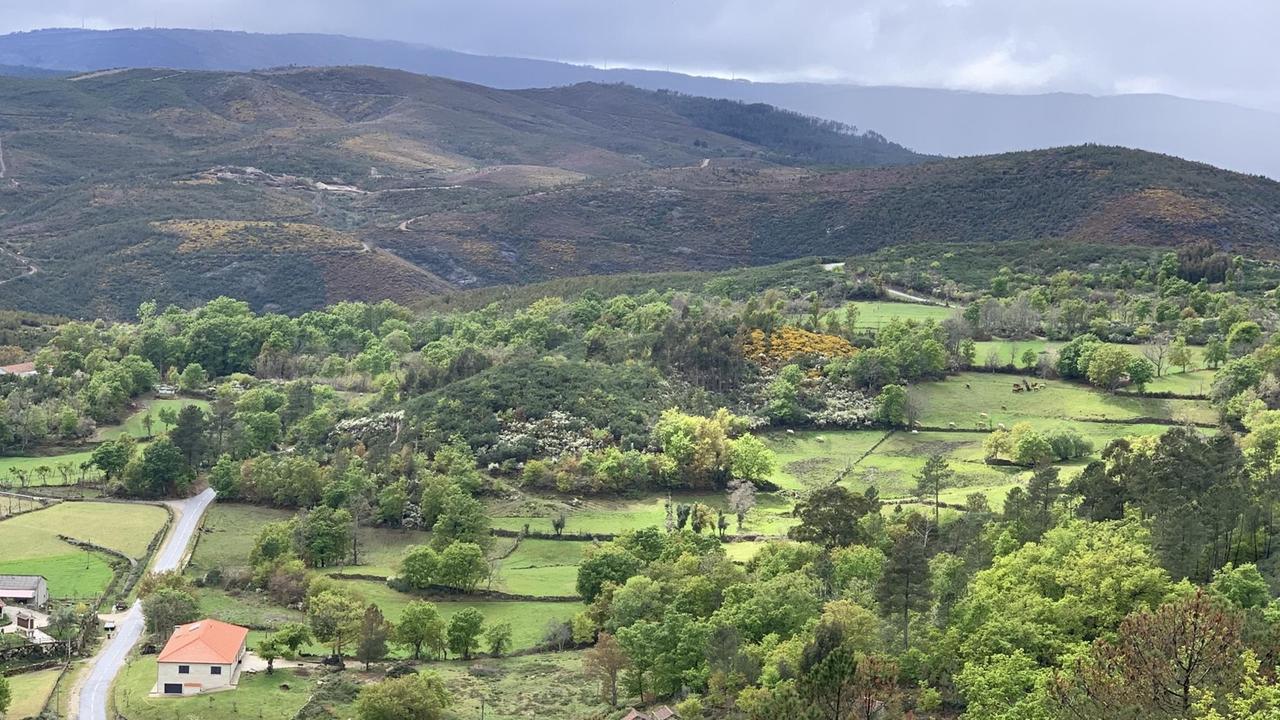 Eine grüne Landschaft mit einigen Häusern und einer schmalen Straße, viele Hügel bis zum Horizont. Eine grüne Landschaft mit einigen Häusern und einer schmalen Straße, viele Hügel bis zum Horizont.