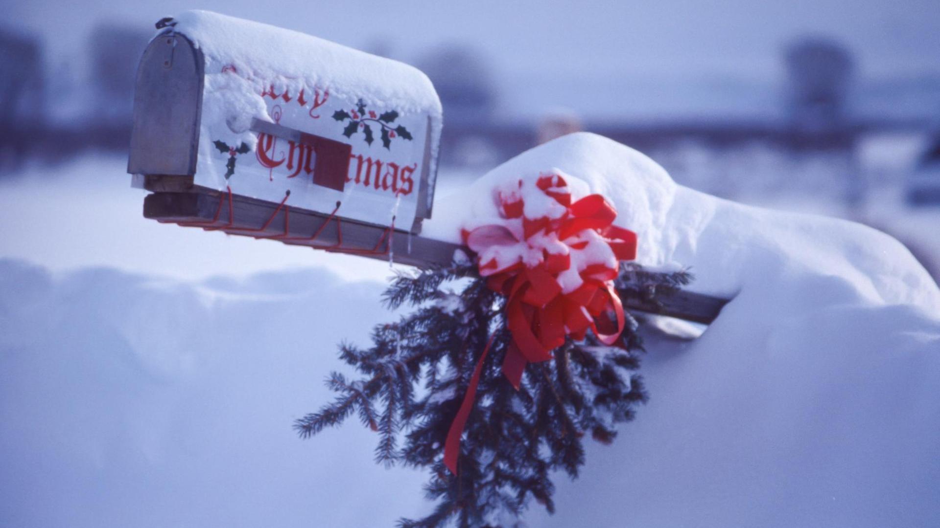 Ein amerikanischer Briefkasten, eingeschneit, mit weihnachtlichem Schmuck und Tannenzweig.