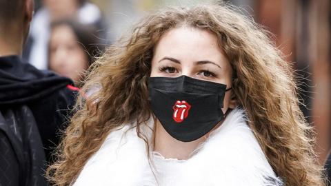 Eine junge Frau mit einer schwarzen Gesichtsmaske, auf der die berühmte Rolling Stones Zunge aufgedruckt ist. 13. März 2020, Brüssel, Belgien.