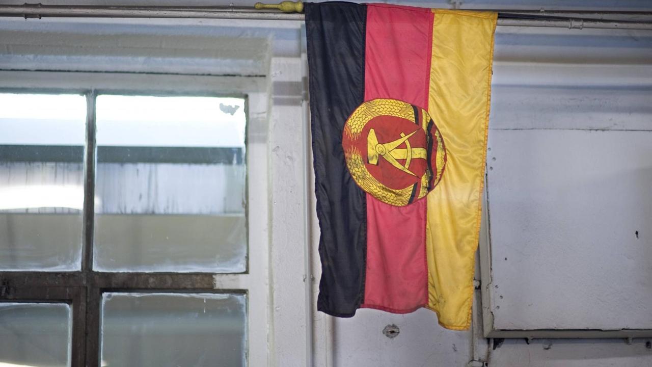 Eine Flagge der ehemaligen DDR hängt in einem Raum mit Fenster. Eine Flagge der ehemaligen DDR hängt in einem Raum mit Fenster.