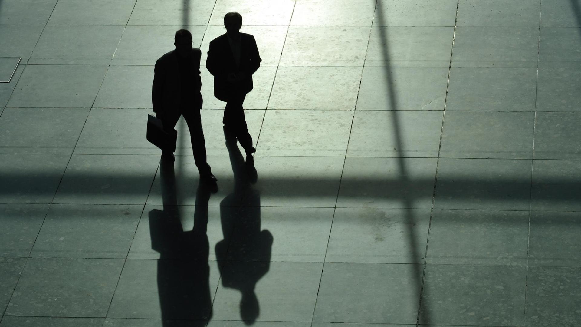 Zwei Männer im Anzug, von denen einer einen Aktenkoffer trägt, werfen am 24.03.2010 in Stuttgart lange Schatten. Zwei Männer im Anzug, von denen einer einen Aktenkoffer trägt, werfen am 24.03.2010 in Stuttgart lange Schatten.
