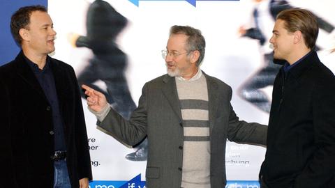 Die US-Schauspieler Leonardo DiCaprio (r.) und Tom Hanks (l.) sowie der Regisseur Steven Spielberg stehen am 26.1.2003 in Berlin vor einem Kinoplakat zu ihrem Streifen "Catch Me If You Can".