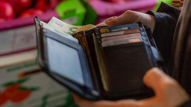 Eine Frau holt einen 5-Euroschein aus ihrem Portemonnaie