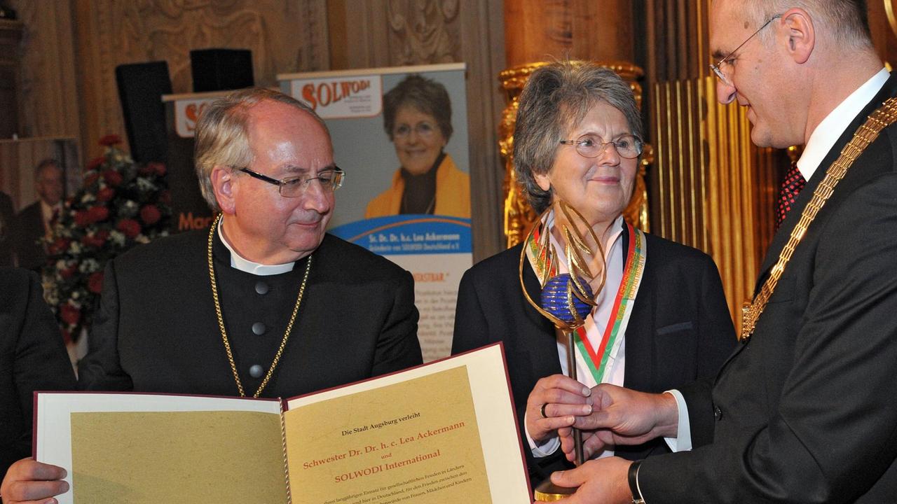 Oberbürgermeister Kurt Gribl (CSU, r) überreicht zusammen mit Regionalbischof Michael Grabow am 22.11.2014 in Augsburg (Bayern) der Ordensschwester Lea Ackermann den Preis "Augsburger Friedensfest 2014". Ackermann erhielt den mit 12.500 Euro dotierten Preis für ihre Hilfs-und Menschenrechtsorganisation Organisation "SOLWODI". Foto: Stefan Puchner/dpa | Verwendung weltweit Oberbürgermeister Kurt Gribl (CSU, r) überreicht zusammen mit Regionalbischof Michael Grabow am 22.11.2014 in Augsburg (Bayern) der Ordensschwester Lea Ackermann den Preis "Augsburger Friedensfest 2014". Ackermann erhielt den mit 12.500 Euro dotierten Preis für ihre Hilfs-und Menschenrechtsorganisation Organisation "SOLWODI". Foto: Stefan Puchner/dpa | Verwendung weltweit