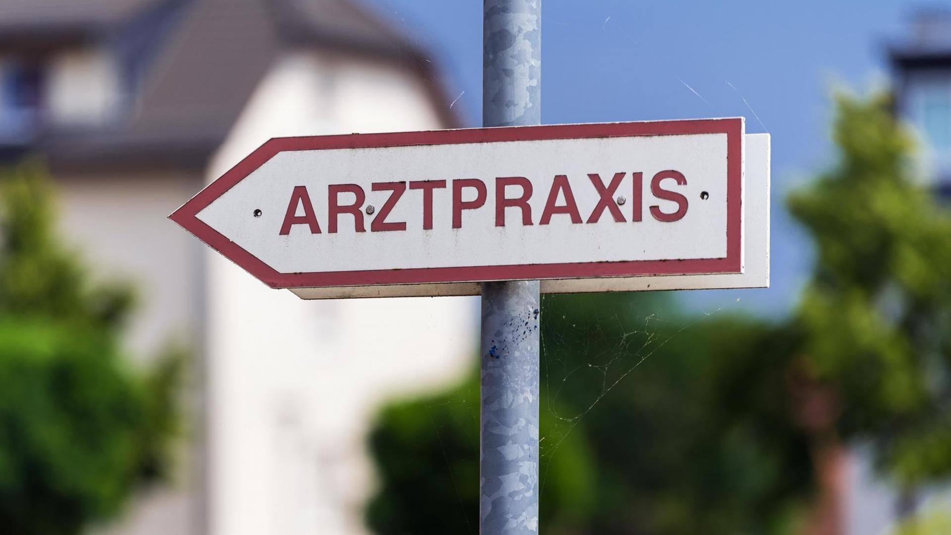 Ein "Arztpraxis"-Schild, im Hintergrund ist verschwommen ein Haus zu sehen Ein "Arztpraxis"-Schild, im Hintergrund ist verschwommen ein Haus zu sehen