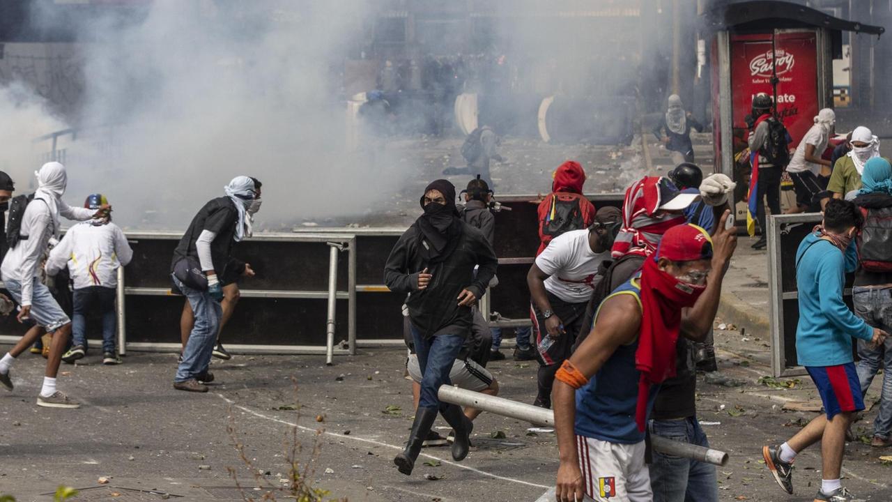 Vermummte Demonstranten suchen Schutz vor dem Tränengas bei Zusammenstößen mit Sicherheitskräften. Vermummte Demonstranten suchen Schutz vor dem Tränengas bei Zusammenstößen mit Sicherheitskräften.