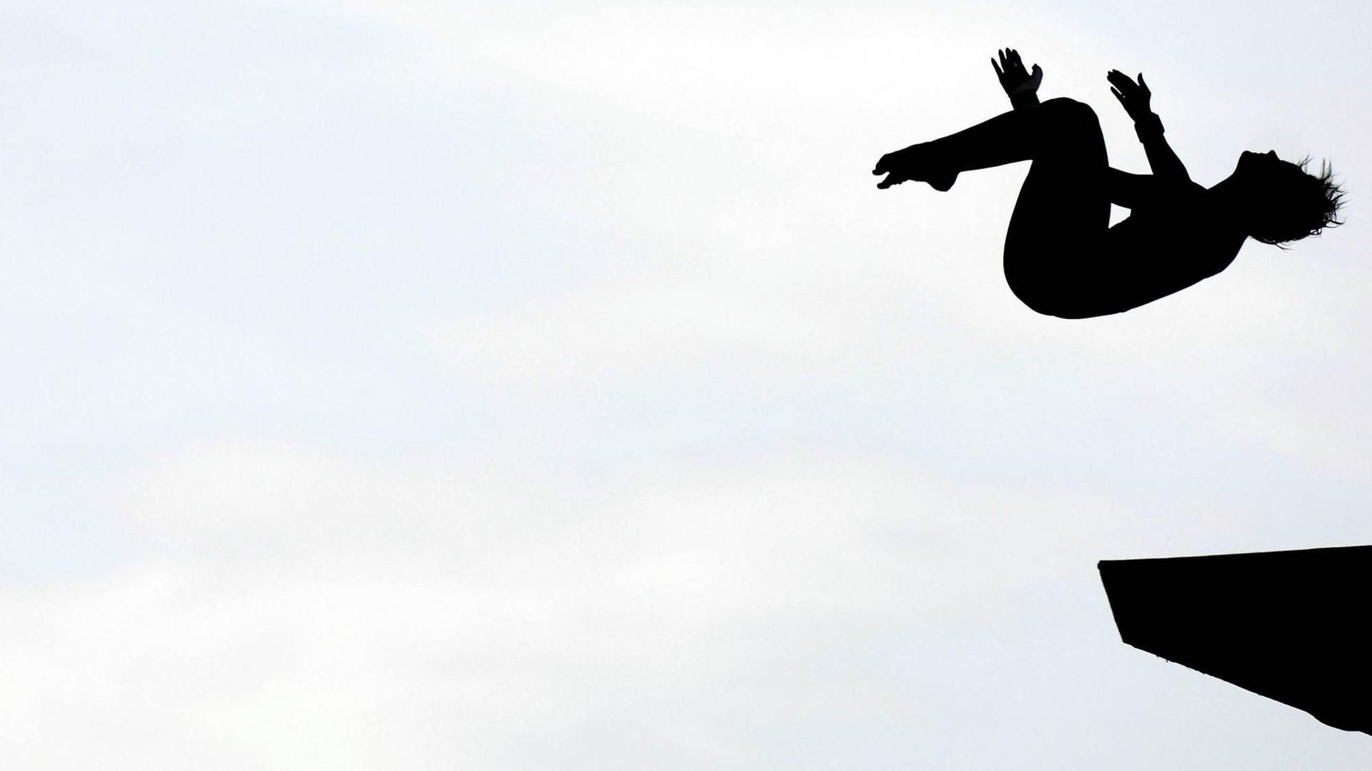 Die Silhouette einer Turmspingerin kurz nach dem Absprung Die Silhouette einer Turmspingerin kurz nach dem Absprung