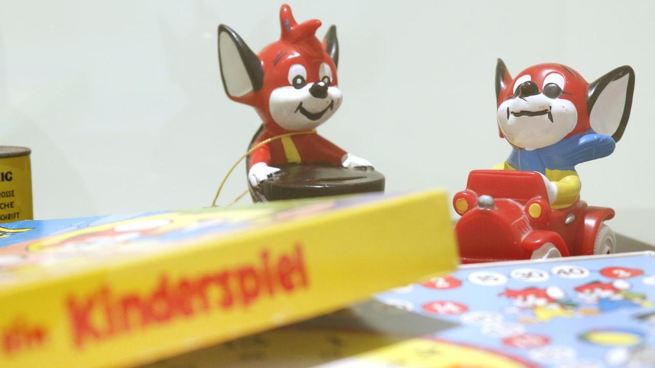 Zwei Spielfiguren der Comicreihe "Fix und Foxi" stehen neben der Verpackung eines Kinderspiels