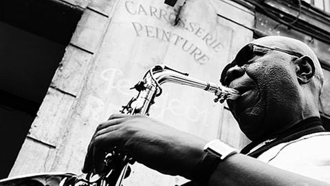 Der Saxophonist Manu Dibango mit seinem Instrument (Schwarz-Weiß-Aufnahme)