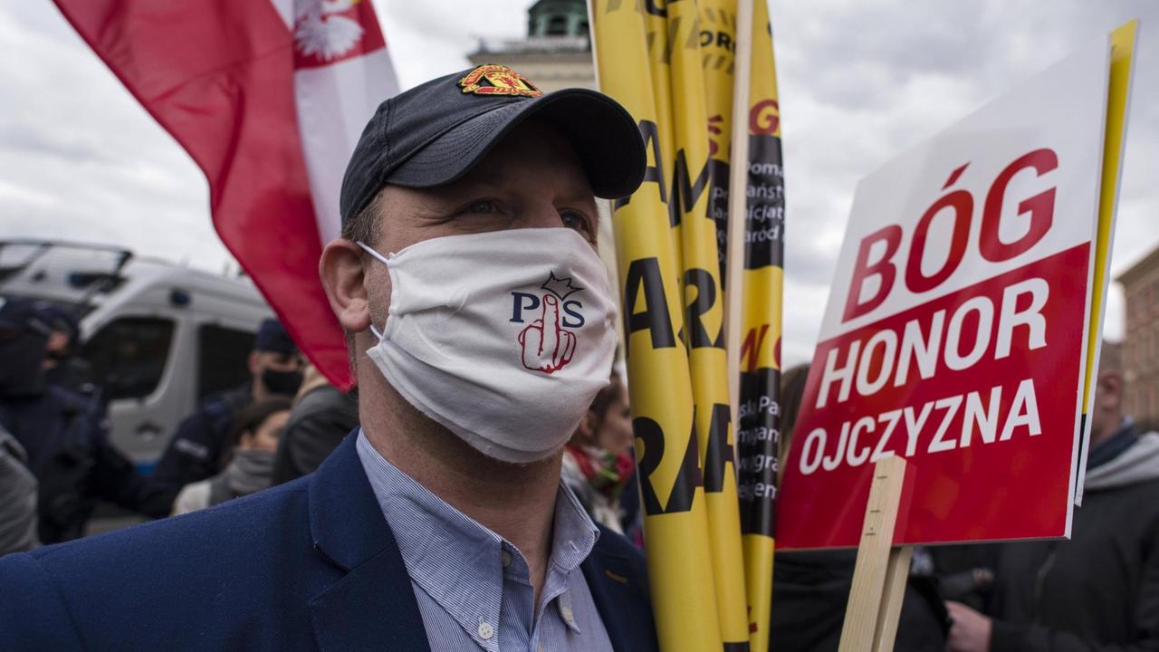 Demonstrant in Warschau bei Protest gegen Corona-Beschränkungen in Polen. Auf seinem Mundschutz steht ein kritischen Statement gegen die Regierungspartei PiS. Demonstrant in Warschau bei Protest gegen Corona-Beschränkungen in Polen. Auf seinem Mundschutz steht ein kritischen Statement gegen die Regierungspartei PiS.