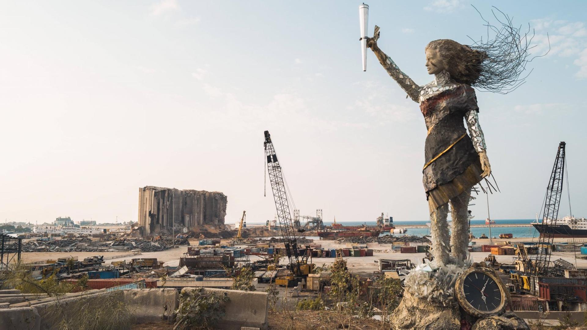 Eine Statue der libanesischen Künstlerin Hayat Nazer aus Glasresten, Trümmern und einer kaputten Uhr, die die Zeit der Megaexplosion im Hafen von Beirut anzeigt. Eine Statue der libanesischen Künstlerin Hayat Nazer aus Glasresten, Trümmern und einer kaputten Uhr, die die Zeit der Megaexplosion im Hafen von Beirut anzeigt.