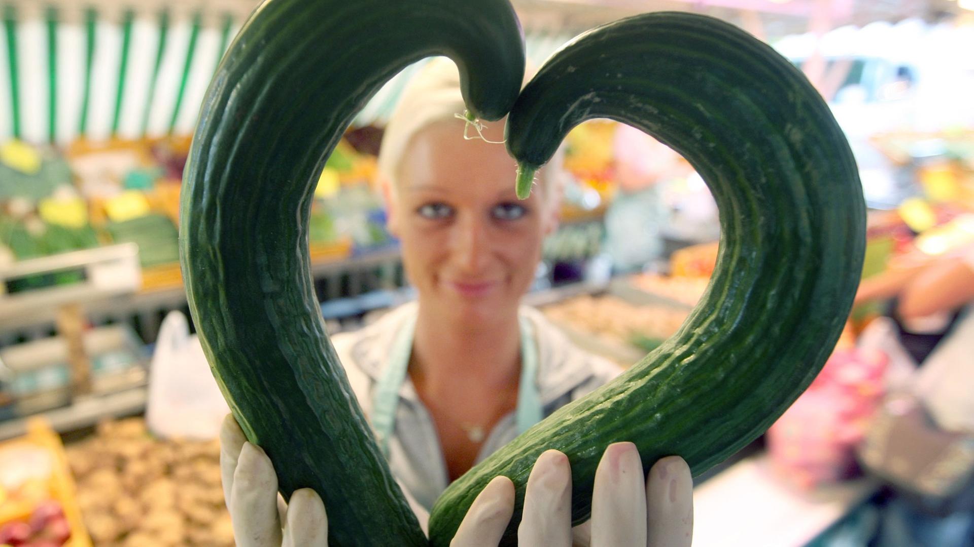 Eine Gemüsehändlerin zeigt am 30.06.2009 auf dem Isemarkt in Hamburg zwei krumme Gurken in Herzform. Eine Gemüsehändlerin zeigt am 30.06.2009 auf dem Isemarkt in Hamburg zwei krumme Gurken in Herzform.