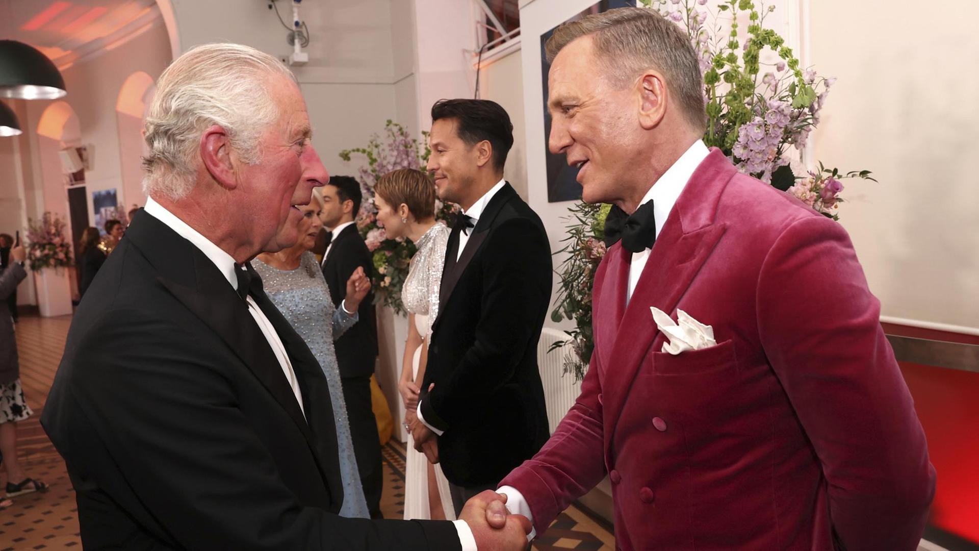 Prinz Charles und Daniel Craig geben sich die Hand.