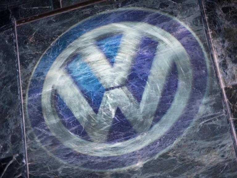 Das Logo von VW mit einer zerkratzten Glasplatte darüber.