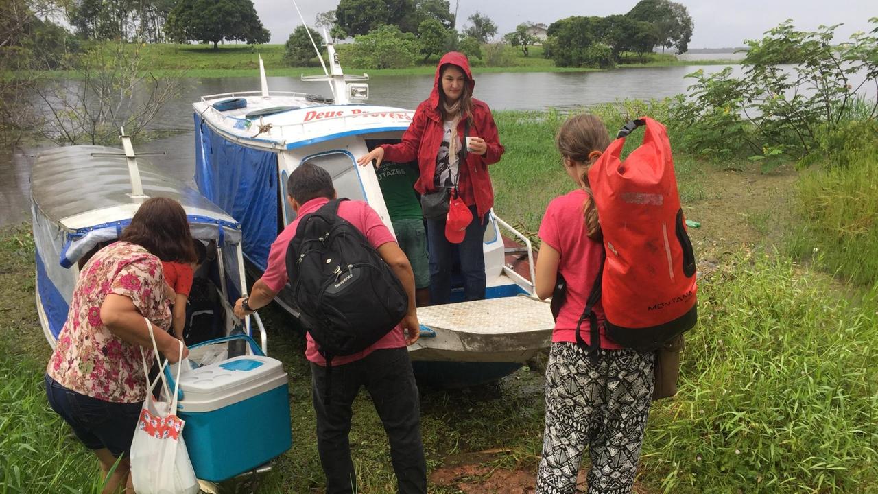 Einige Leute in Regenklamotten steigen in ein Motorboot. Einige Leute in Regenklamotten steigen in ein Motorboot.