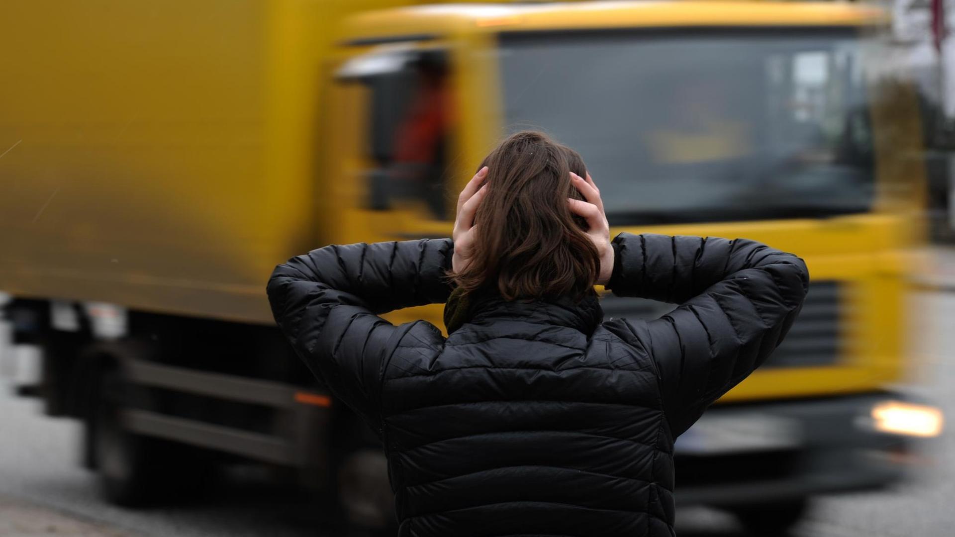 Eine Frau hält sich in Hamburg vor einem nahenden LKW die Ohren zu. Eine Frau hält sich in Hamburg vor einem nahenden LKW die Ohren zu.