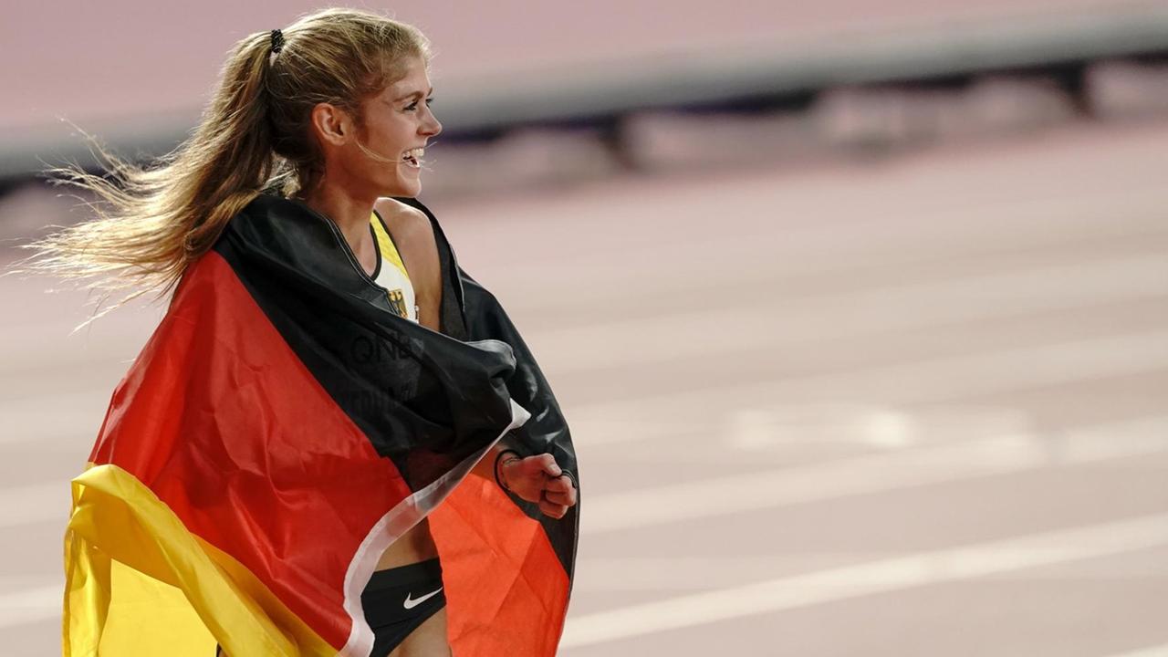 Die Drittplatzierte Konstanze Klosterhalfen aus Deutschland läuft mit einer deutschen Fahne eine Ehrenrunde bei der WM in Doha Die Drittplatzierte Konstanze Klosterhalfen aus Deutschland läuft mit einer deutschen Fahne eine Ehrenrunde bei der WM in Doha