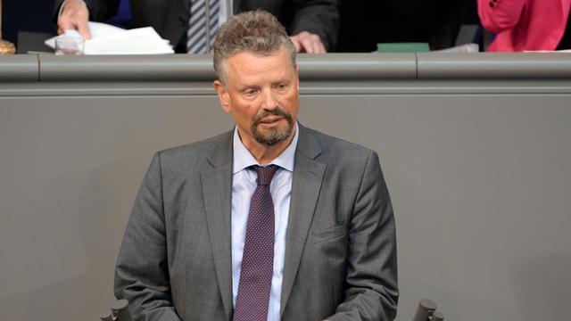 Gernot Erler spricht im grauen Anzug am Rednerpult des Deutschen Bundestages. Er hält sein Manuskript in der Hand.