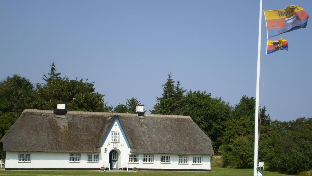 Ein typisches Friesenhaus auf Sylt (Weddingstedt Braderup) mit der friesischen Fahne daneben Ein typisches Friesenhaus auf Sylt (Weddingstedt Braderup) mit der friesischen Fahne daneben