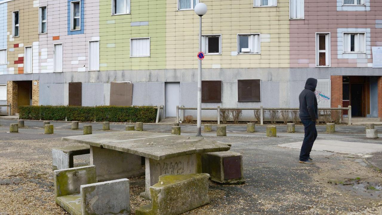 Ein junger Mann mit steht in der Pariser Vorstadt Grigny vor einem Wohnblock. Ein junger Mann mit steht in der Pariser Vorstadt Grigny vor einem Wohnblock.