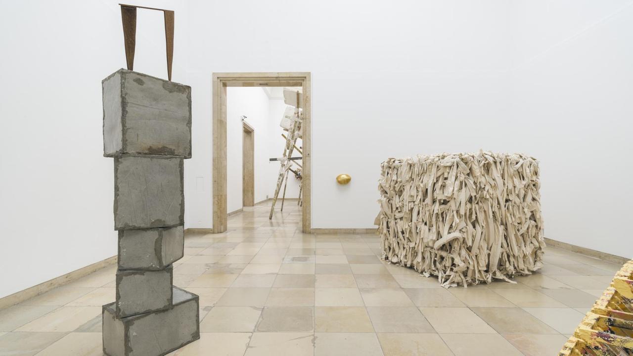 Installationsansicht der Skulptur-Ausstellung von Phyllida Barlow im Haus der Kunst in München. Ein Würfel, rundherm mit weißen Leinwandfransen bedeckt, heißt "Shedmesh".