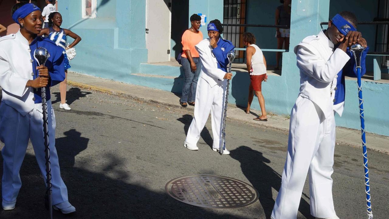 Drei Bürger der U.S. Virgin Islands tragen weiß-blaue Kostüme für eine Parade.