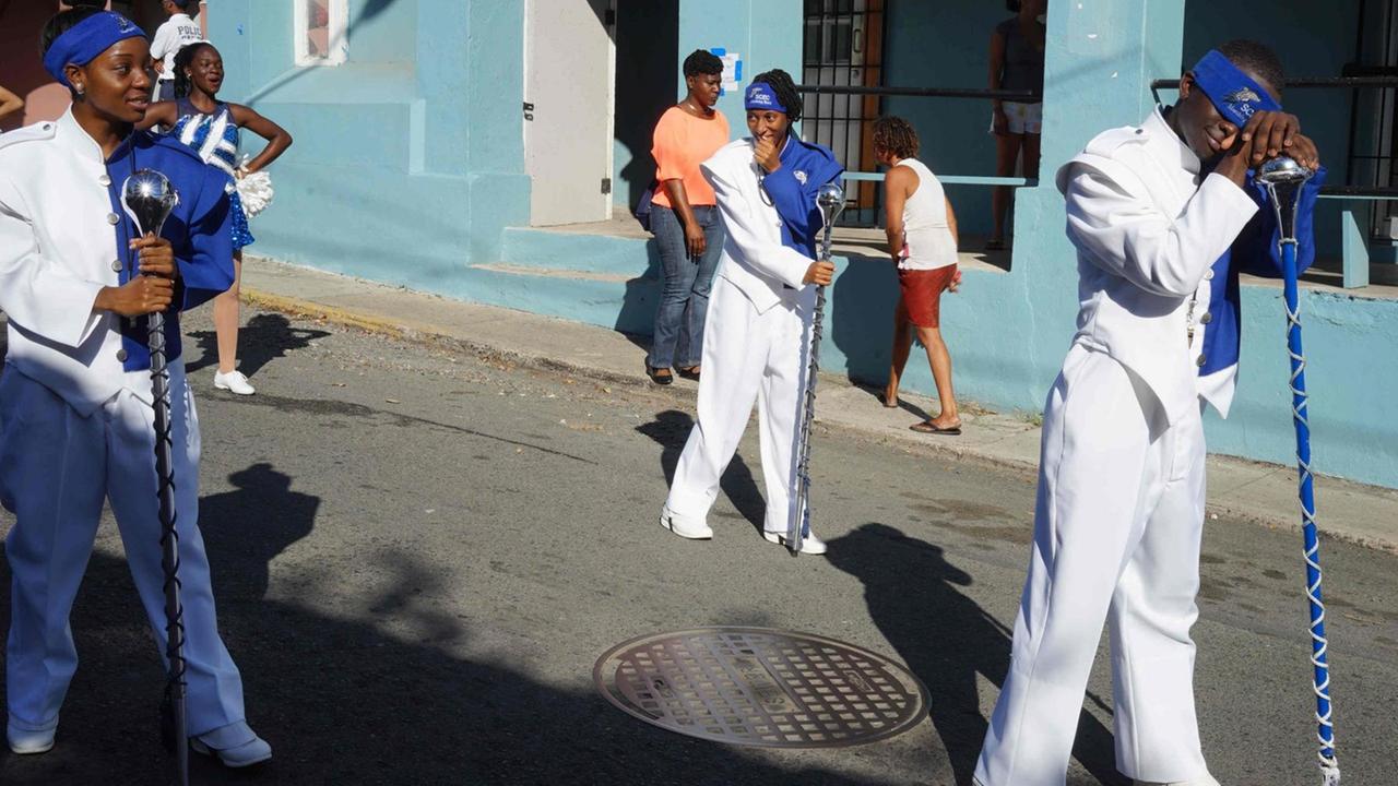 Drei Bürger der U.S. Virgin Islands tragen weiß-blaue Kostüme für eine Parade. Drei Bürger der U.S. Virgin Islands tragen weiß-blaue Kostüme für eine Parade.