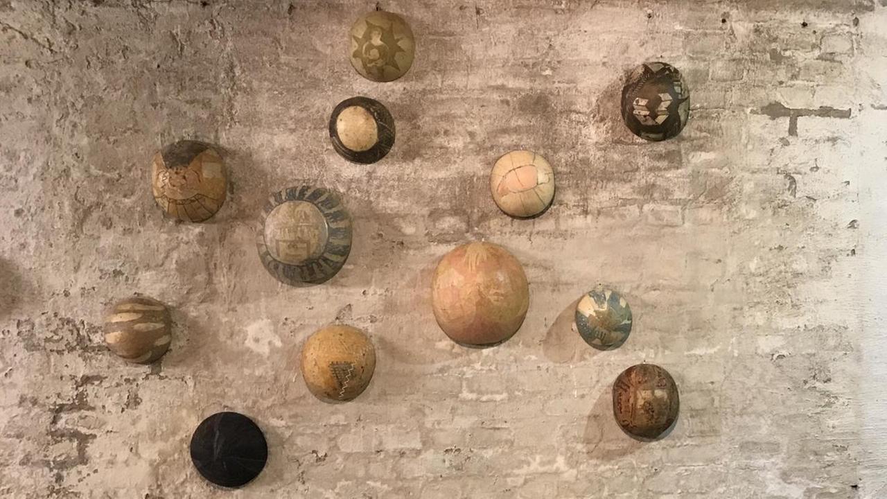 Eine Kunstwerk aus bemalten Kürbissen der Künstlerin Greta Wildhage hängt an einer Bunkerwand