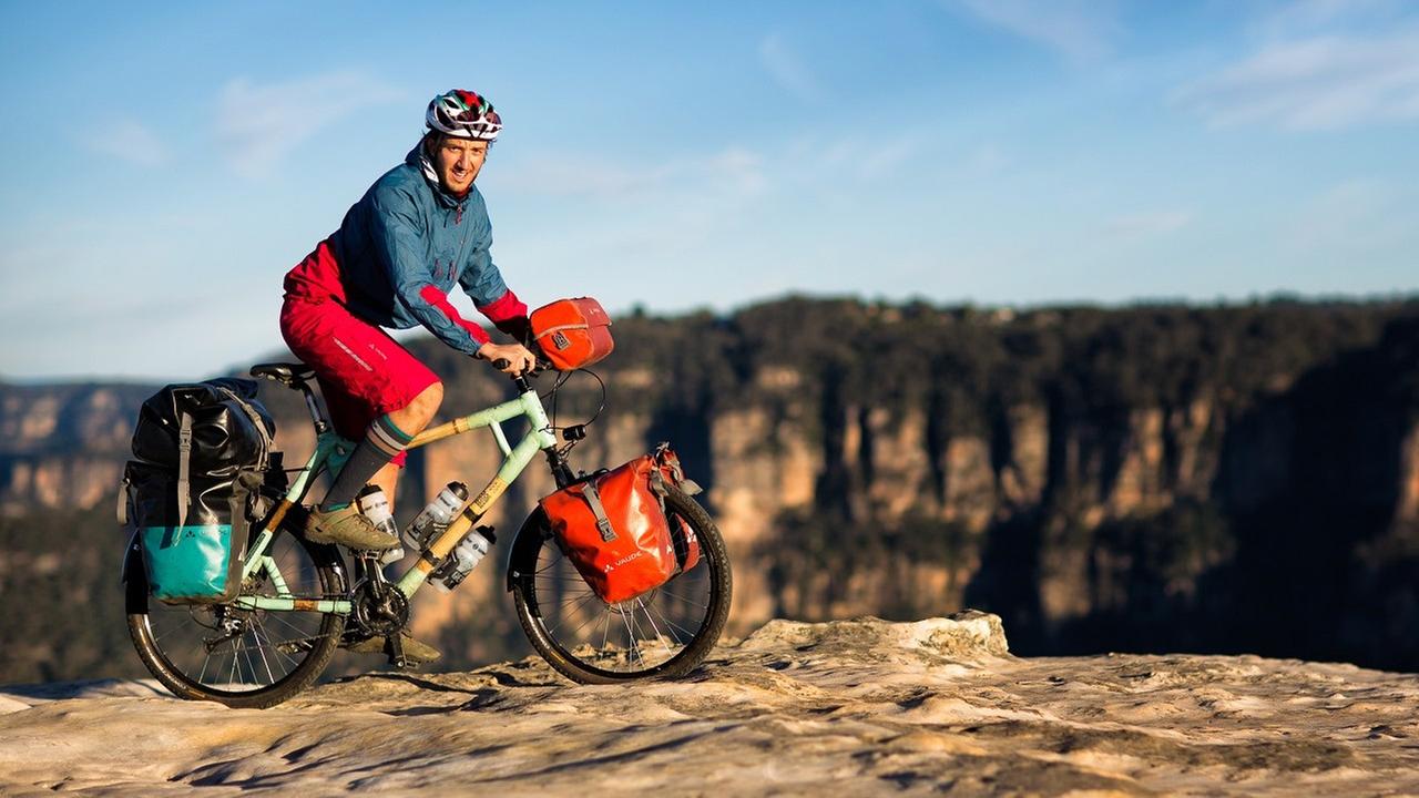 Bamboo Basti fährt auf seinem Fahrrad aus Bambus an einem felsigen Abgrund in Australien entlang. Bamboo Basti fährt auf seinem Fahrrad aus Bambus an einem felsigen Abgrund in Australien entlang.