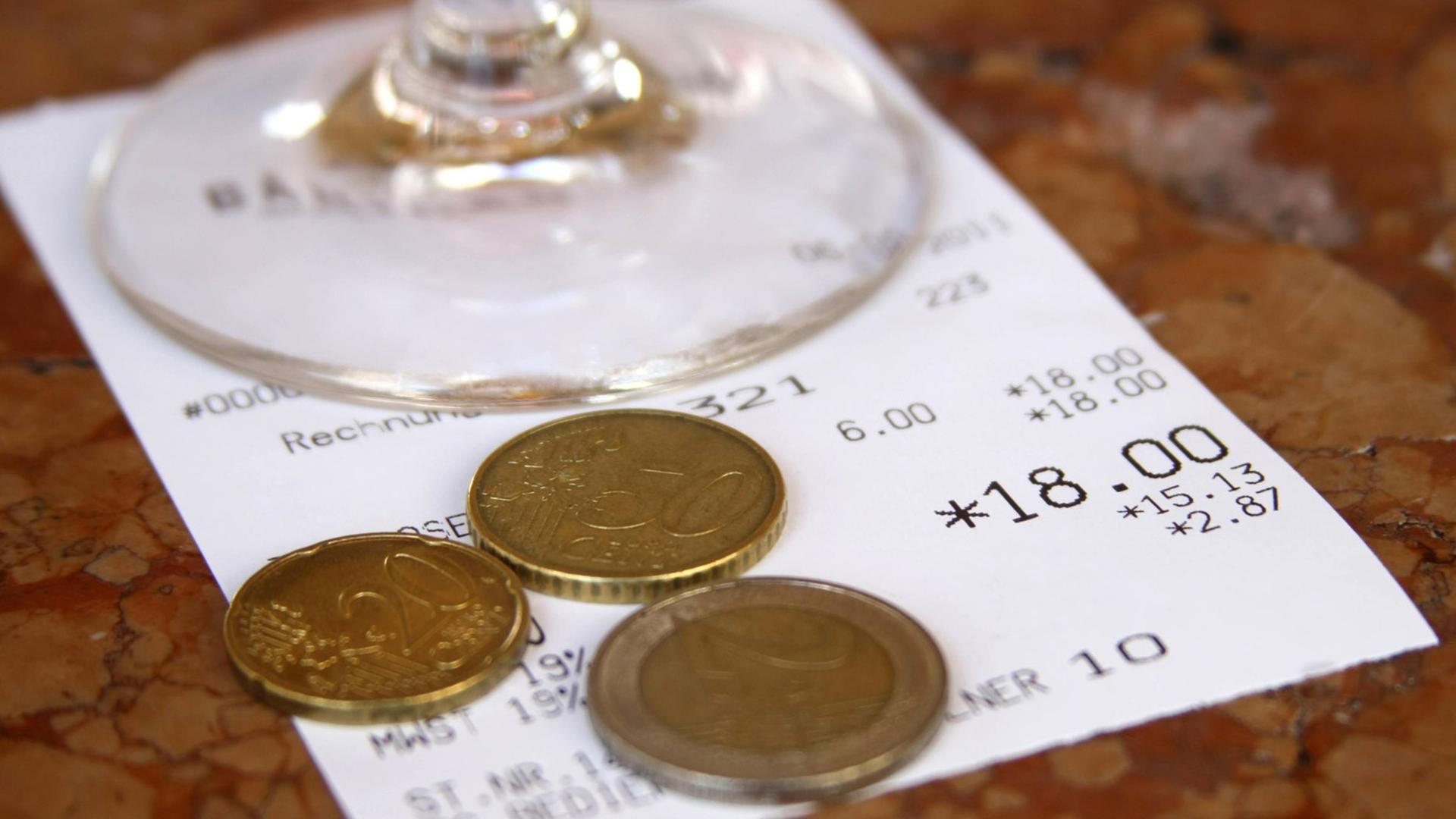 Quittung eines gastronomischen Betriebs mit Glas und Betrag in Euro und Münzen als Trinkgeld Quittung eines gastronomischen Betriebs mit Glas und Betrag in Euro und Münzen als Trinkgeld