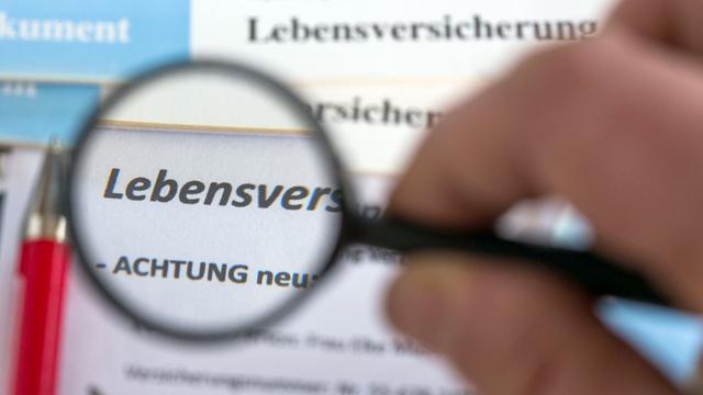 Der Schriftzug "Lebensversicherung" ist am 04.12.2014 in Schwerin (Mecklenburg-Vorpommern) unter einer Lupe auf Unterlagen für Versicherungen zum Teil zu lesen.